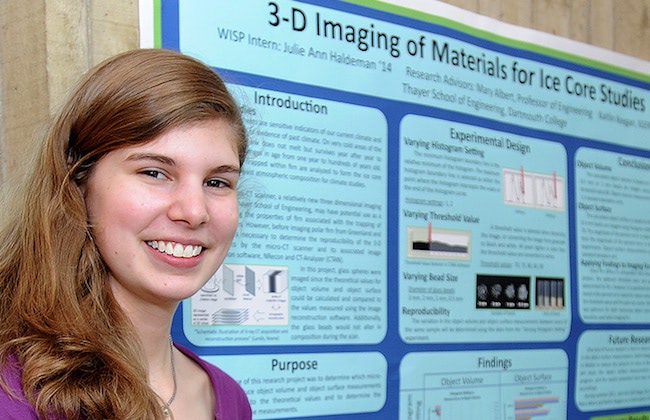 A member of Society of Women Engineers at Dartmouth Engineering smiling in front of a poster presentation.